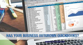 Laptop displaying a complex spreadsheet with a banner about outgrowing QuickBooks.