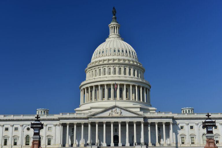 The US Capitol building dome under a clear blue sky.