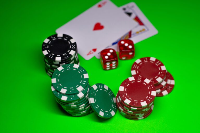 Casino chips, red dice, and playing cards on a green gaming table.