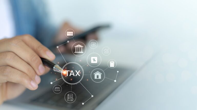 Hand pointing to a glowing "TAX" icon on a digital financial interface.